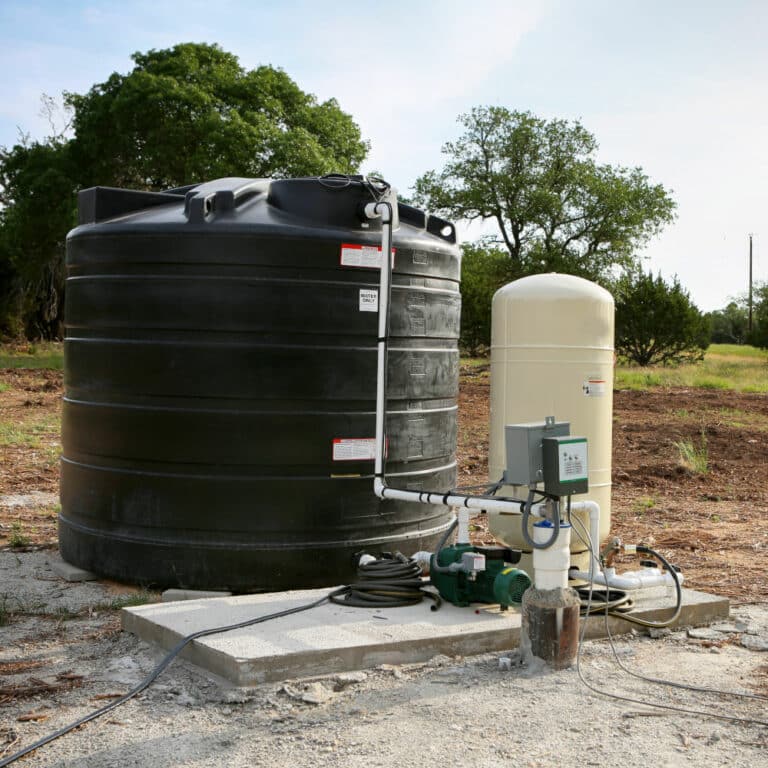 Deep water well set up, country side construction. Drilled draw well with pressure switch and storage tank.